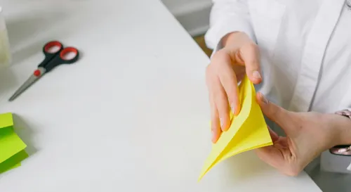 她低著頭，動作緩慢而專注，將紙張一角一角地摺好